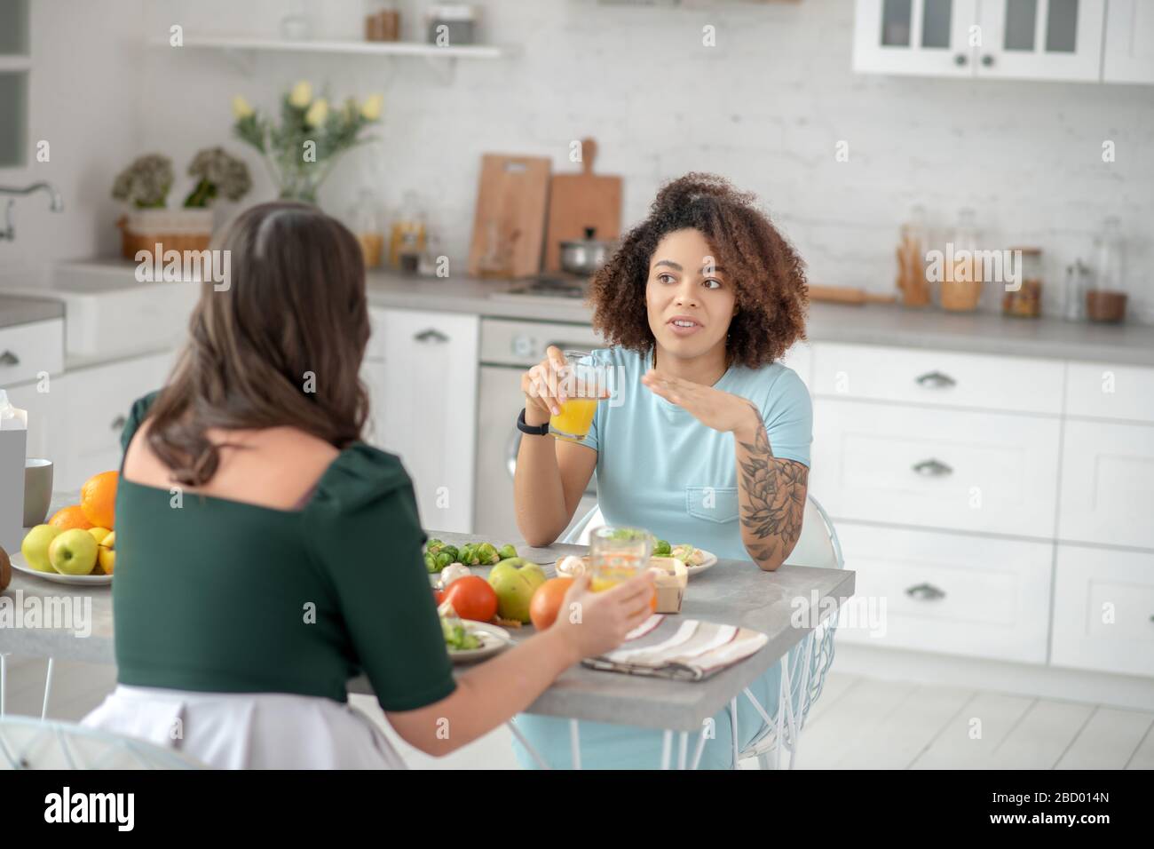 Deux femmes prenant le petit déjeuner, parler dans la cuisine à la maison. Banque D'Images