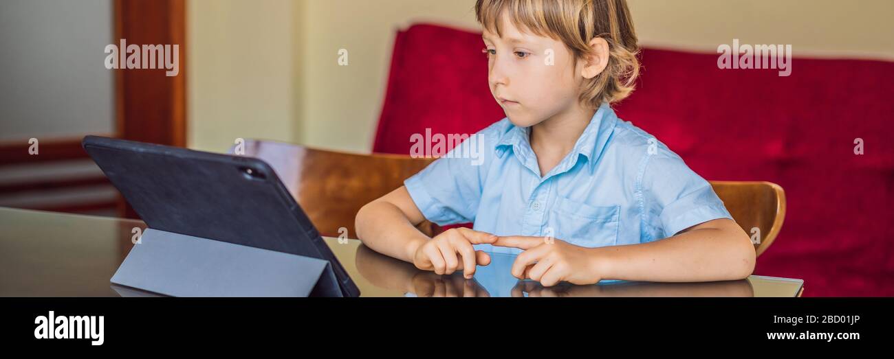 Garçon étudiant en ligne à la maison à l'aide d'une tablette. Étudier pendant la quarantaine. BANNIÈRE mondiale de virus pandémique covid19, FORMAT LONG Banque D'Images