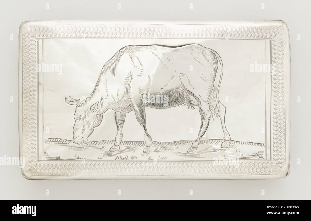 Boîte à tabac. Recherche dans la boîte plate ProgressRectangle avec couvercle à charnière. Face inférieure gravée de lignes parallèles formant des rayures. Bords extérieurs avec double bande de lignes gravées. Couvrir avec la bordure tournée du moteur entourant l'image gravée de l'herbe de vache mangeant. Boîte à tabac Banque D'Images