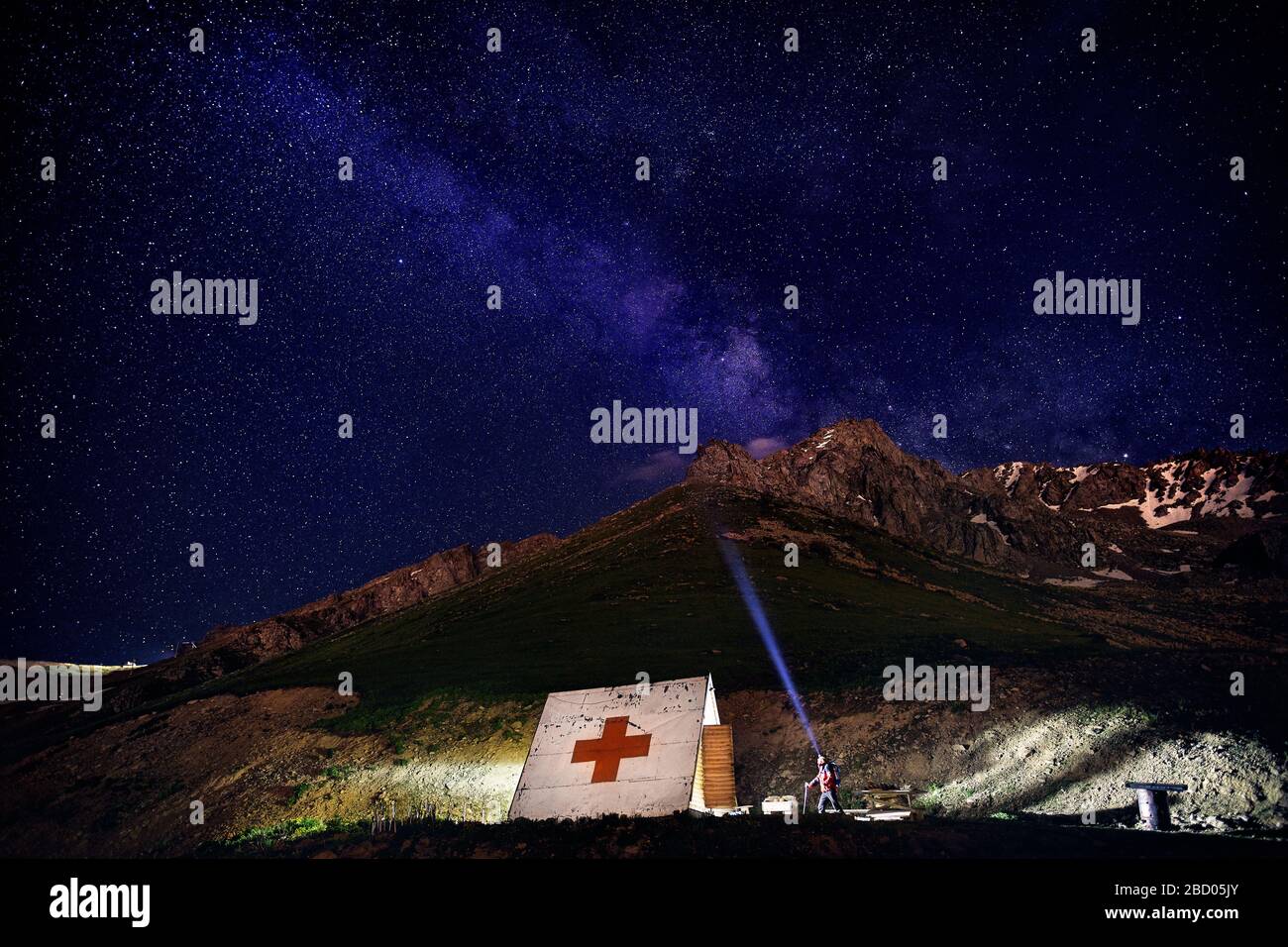 Beau ciel de nuit avec des étoiles et silhouette d'homme pointant son voyant de près de house avec medical dans la montagne dans station de ski Banque D'Images