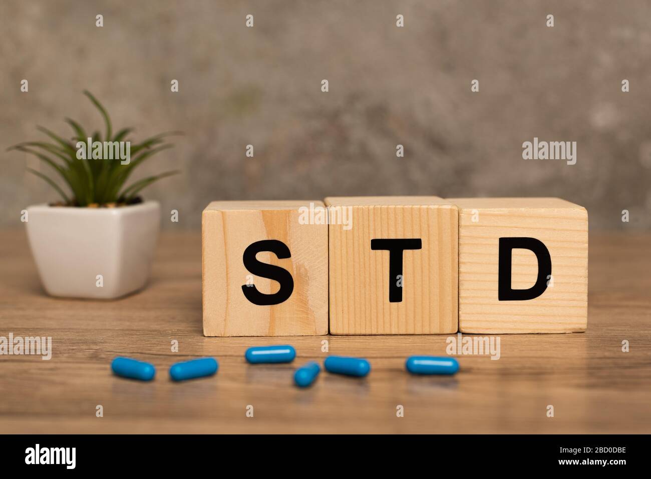 Foyer sélectif de blocs avec des lettres std, des pilules et des plantes sur table en bois sur fond gris Banque D'Images