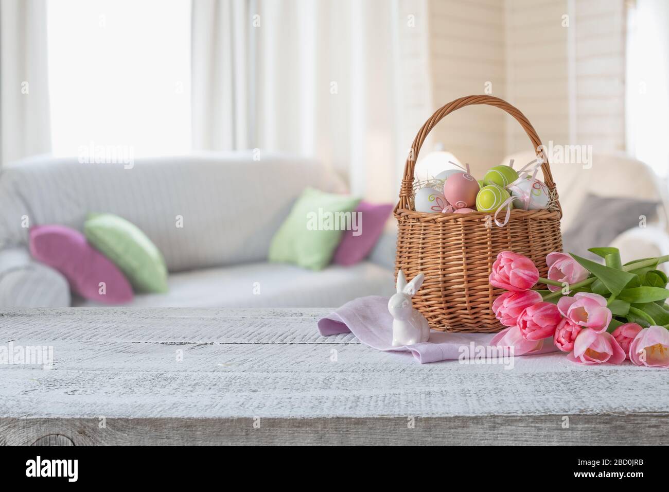 Composition de Pâques avec lapin et œufs colorés dans le panier, bouquet tulipes sur table en bois. Printemps maison intérieur confortable. Espace de conception. Restez à la maison. Banque D'Images