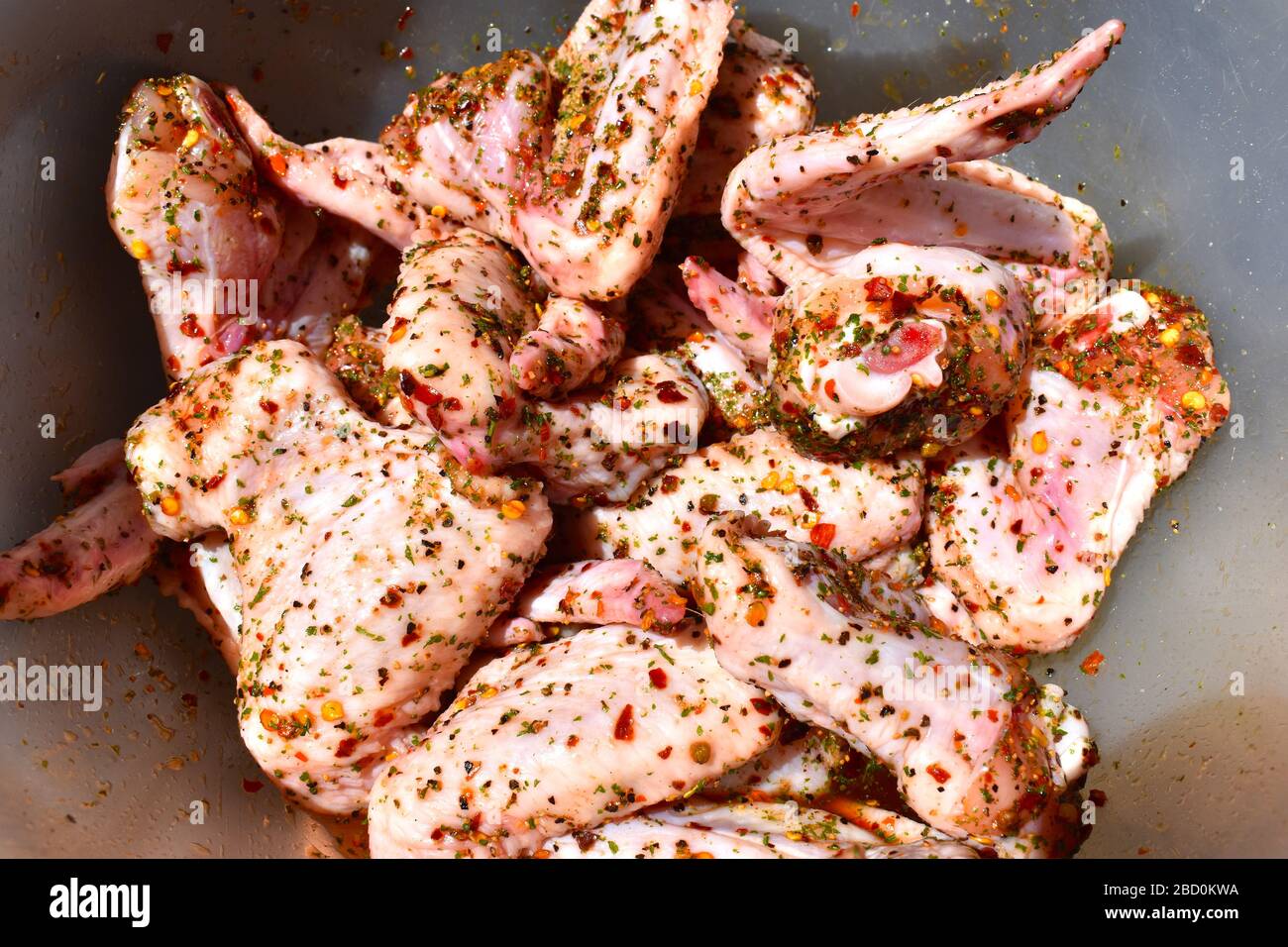 Ailes de poulet de la gamme libre aromatisées aux flocons de piment poivre noir persil séché huile de colza et paprika chaude tendre saine entrée à griller Banque D'Images