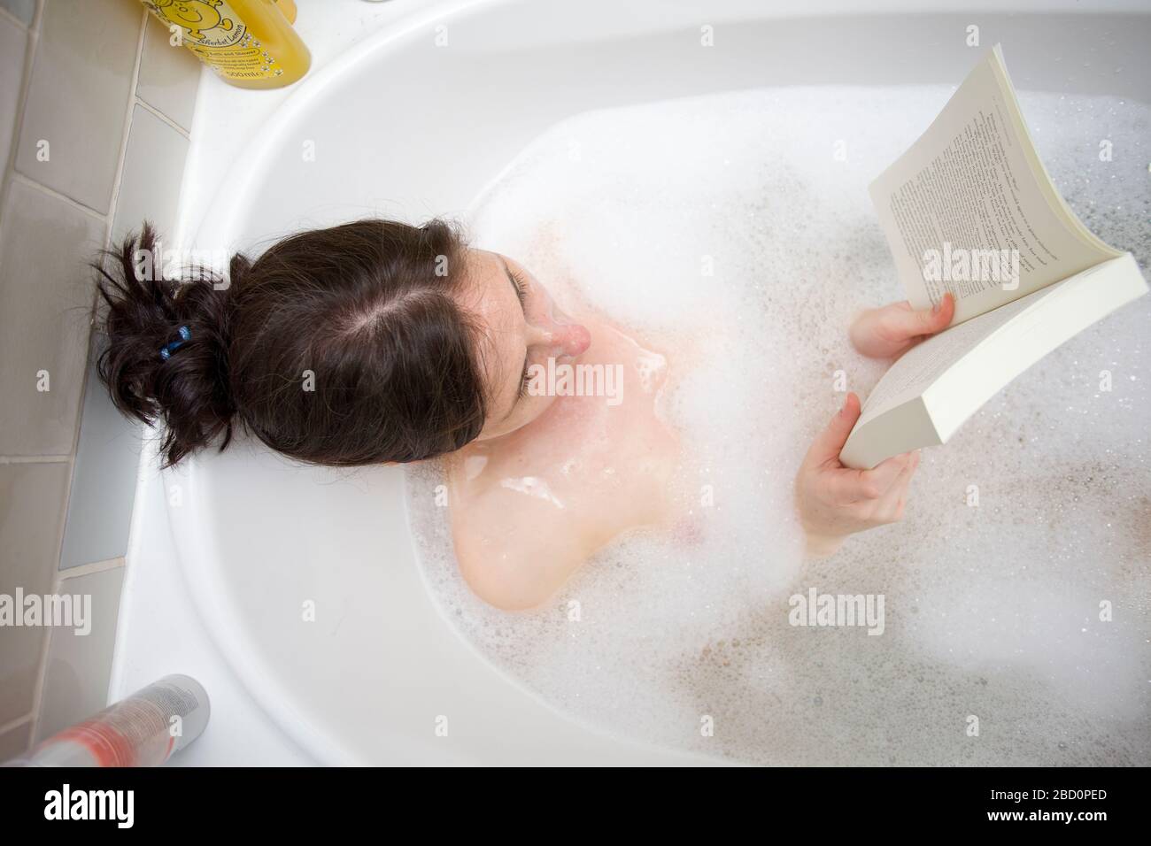 Les jeunes femmes se détendant dans le bain lisant son livre Banque D'Images