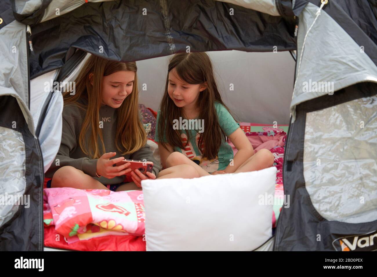 Jeunes filles dans la tente regardant un iPhone Banque D'Images