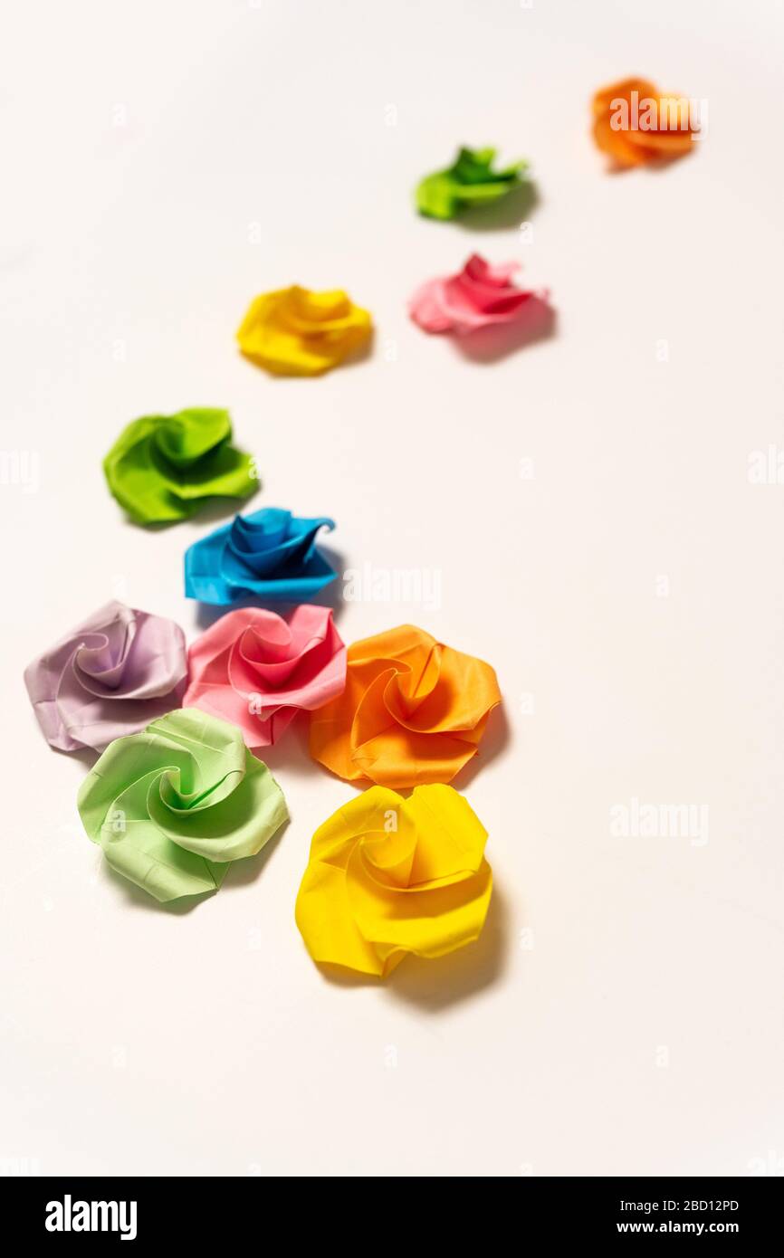 Les fleurs Origami colorées sont vaguement dispersées sur un fond blanc Banque D'Images