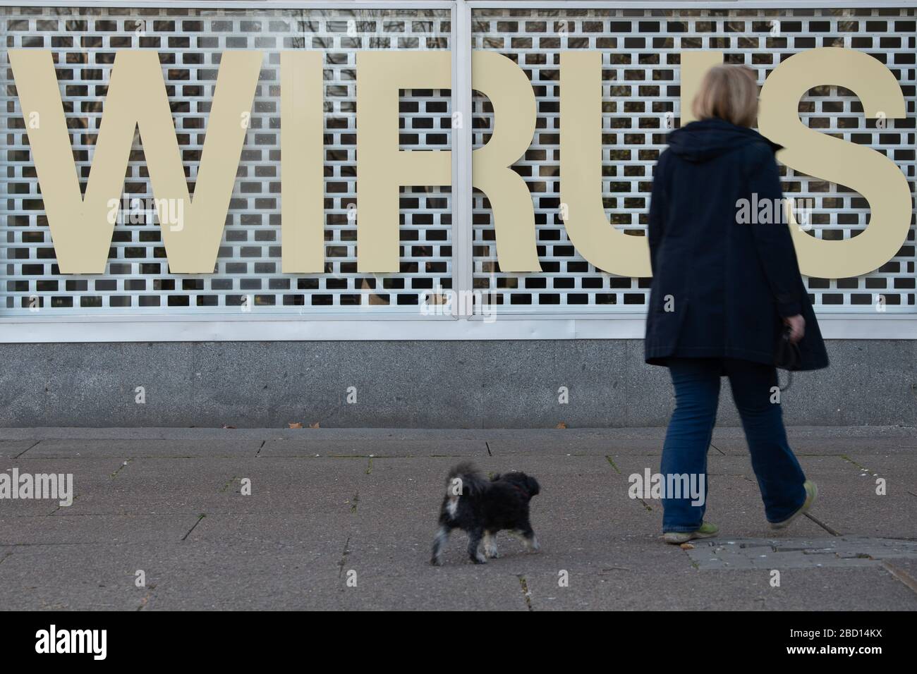 Dresde, Allemagne. 06 avril 2020. Une femme passe devant la fenêtre d'un magasin fermé avec un chien par le lettrage 'Wirus'. Pour ralentir la propagation du coronavirus, le gouvernement fédéral a encore sévèrement limité la vie publique. Crédit: Sebastian Kahnert/dpa-Zentralbild/dpa/Alay Live News Banque D'Images