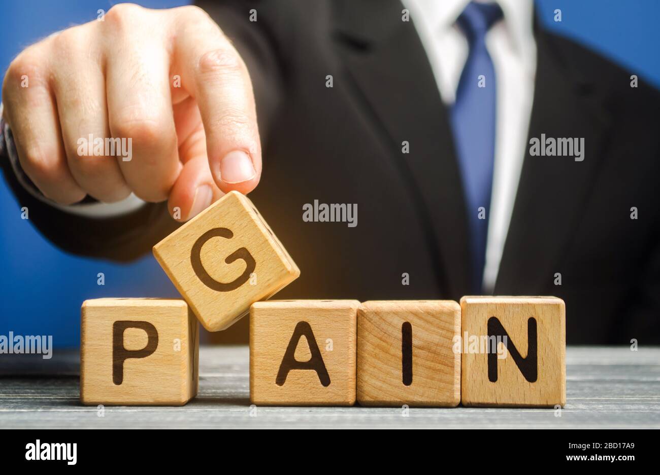Homme d'affaires met des blocs de bois avec les mots Gain, douleur. Motivation, aspiration, concept de réalisation des objectifs. Gestion et changement Banque D'Images