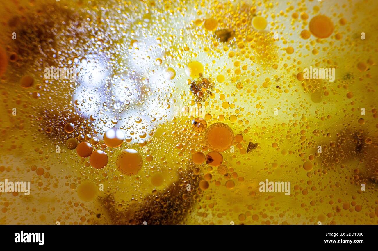 Taches d'huile jaunes sur l'eau. Olive dans une poêle à frire. Images macro de taches graisseuses. Cupcakes jaunes. Liquide de geta. Fondation en velours. Banque D'Images