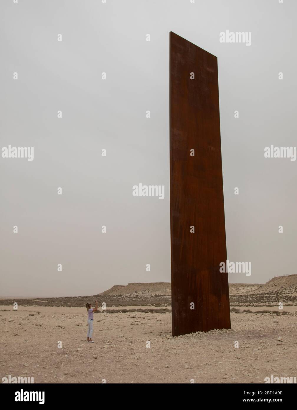 Une femme prenant une photo de l'est-Ouest / Ouest-est par Richard Serra, Desert Sculpture au Qatar donnant un sens d'échelle à la Sculpture et à l'environnement. Banque D'Images