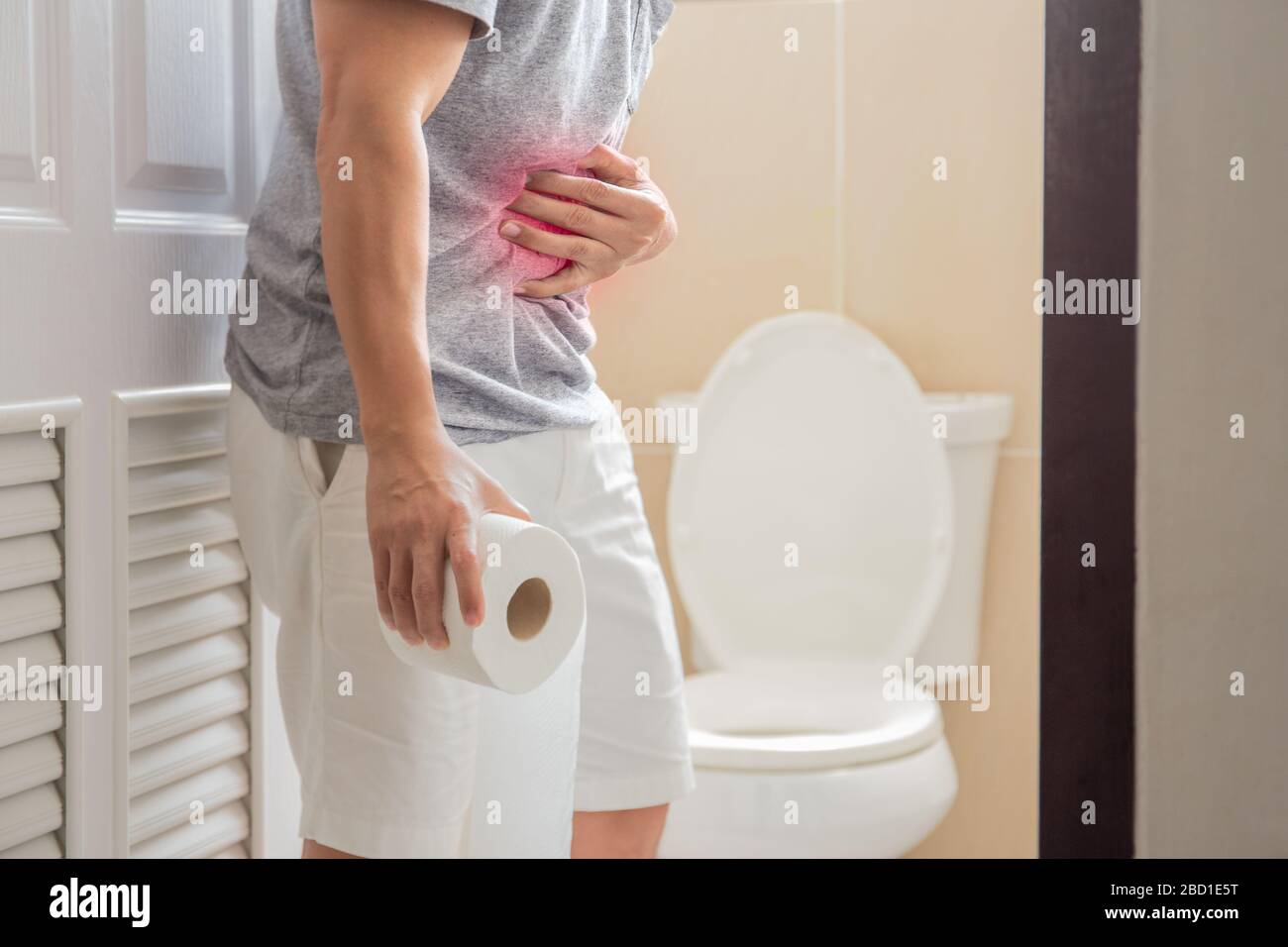Les hommes qui tiennent le rouleau de toilettes ont le concept de symptôme de coronavirus de douleur abdominale. Banque D'Images