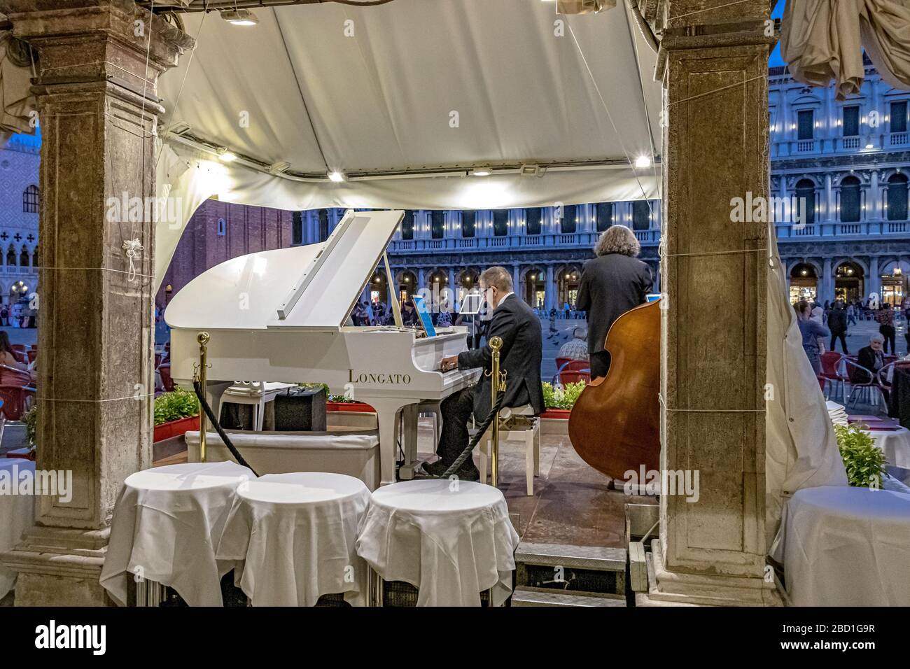 Un homme jouant un piano blanc en début de soirée devant le Ristorante Quadri un restaurant opulent surplombant la place Saint-Marc, Venise, Italie Banque D'Images