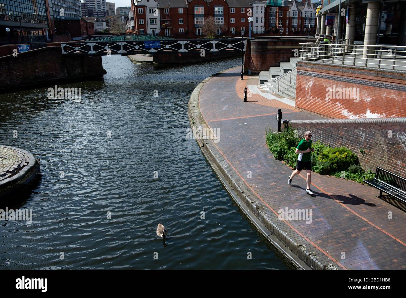 Un homme exerce par un canal dans le centre-ville de Birmingham comme le Canal and River Trust a commencé à mettre en place des panneaux avertissant les gens de limiter l'utilisation des chemins de remorquage de canal et ont eu égard à la distanciation sociale. Banque D'Images