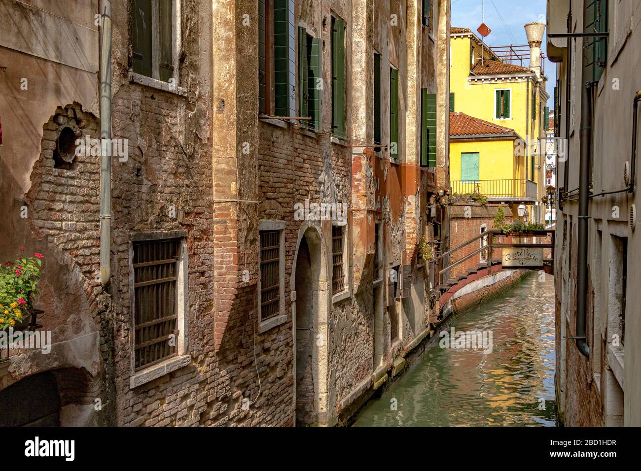Un canal étroit avec un petit pont en bois menant à poste Vecie un restaurant italien près du marché aux poissons du Rialto à Venise, Italie Banque D'Images