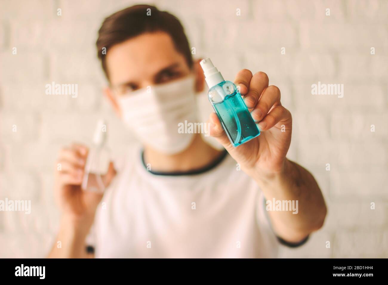 Médecin professionnel dans un masque de protection sur le visage montrant des bouteilles de désinfectant dans les mains. Jeune homme dans un masque médical contenant du gel antibactérien. Personnel Banque D'Images