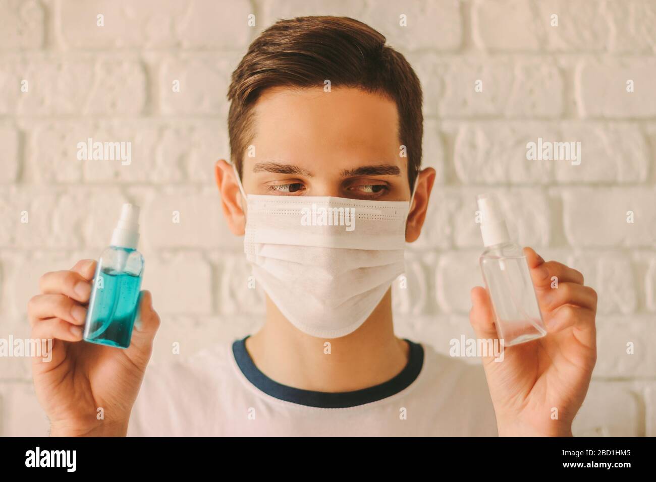 Médecin professionnel dans le masque de protection sur le visage tenir les bouteilles de désinfectant dans les mains. Le jeune homme dans le masque médical montre un gel antibactérien pour la saf personnelle Banque D'Images