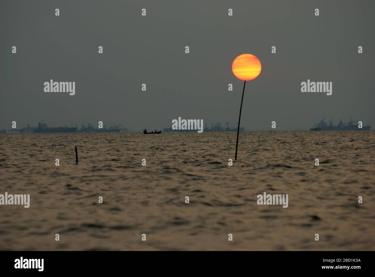 Le cycle complet du soleil, des pôles et le trafic portuaire de Jakarta sur la baie de Jakarta sont vus depuis le village côtier de Marunda à Jakarta, en Indonésie. Banque D'Images