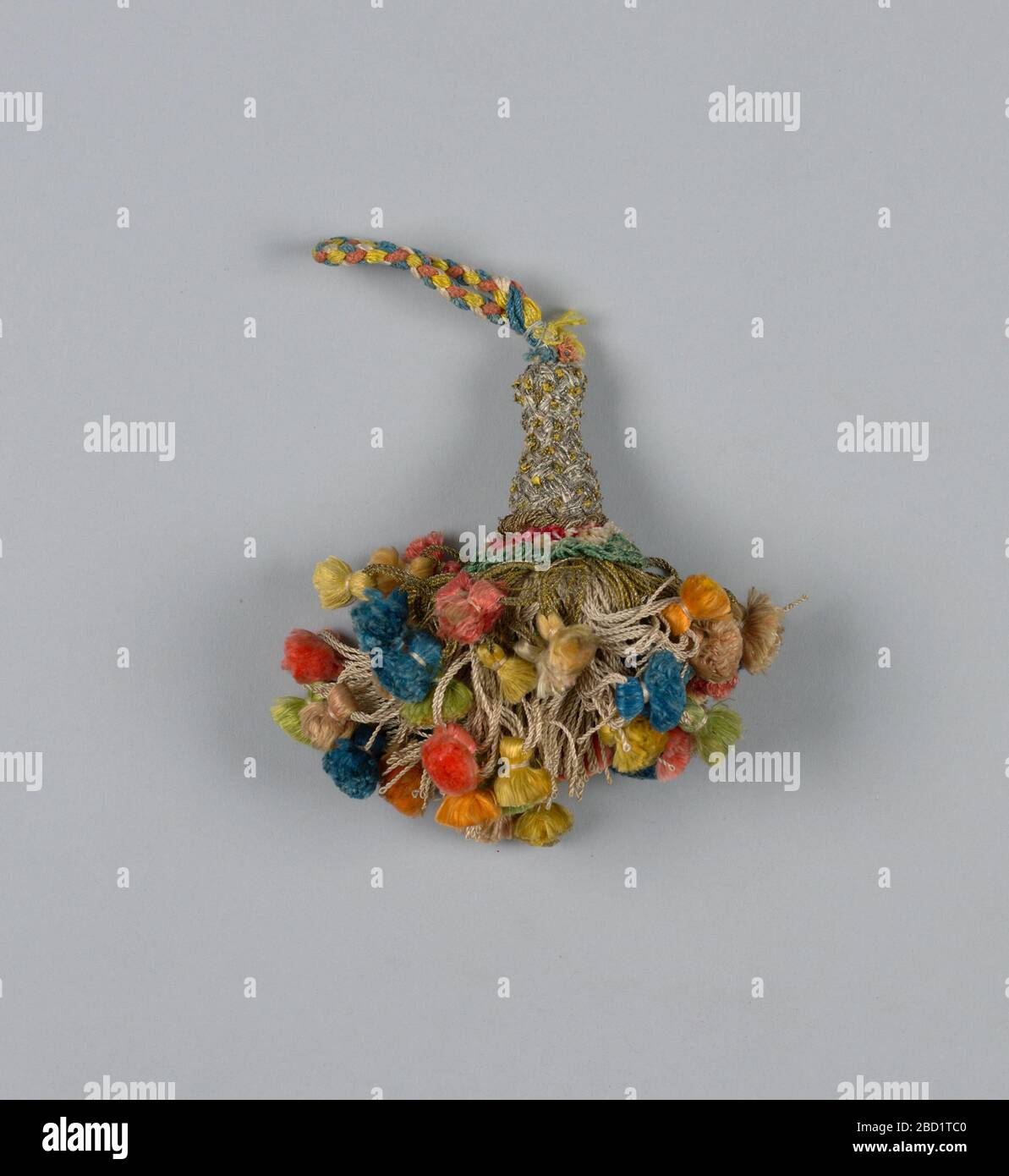 Pampille. Recherche sur ProgressJupe de fils de soie blanche, partiellement recouvert de fils de métal, toutes bouclés et chacune supportant une pampille colorée. Collier en soie et fils métalliques. La tête est en forme de vase et enveloppée dans des fils argentés et dorés. Boucle de fils roses, bleus, jaunes et blancs tressés. Pampille Banque D'Images