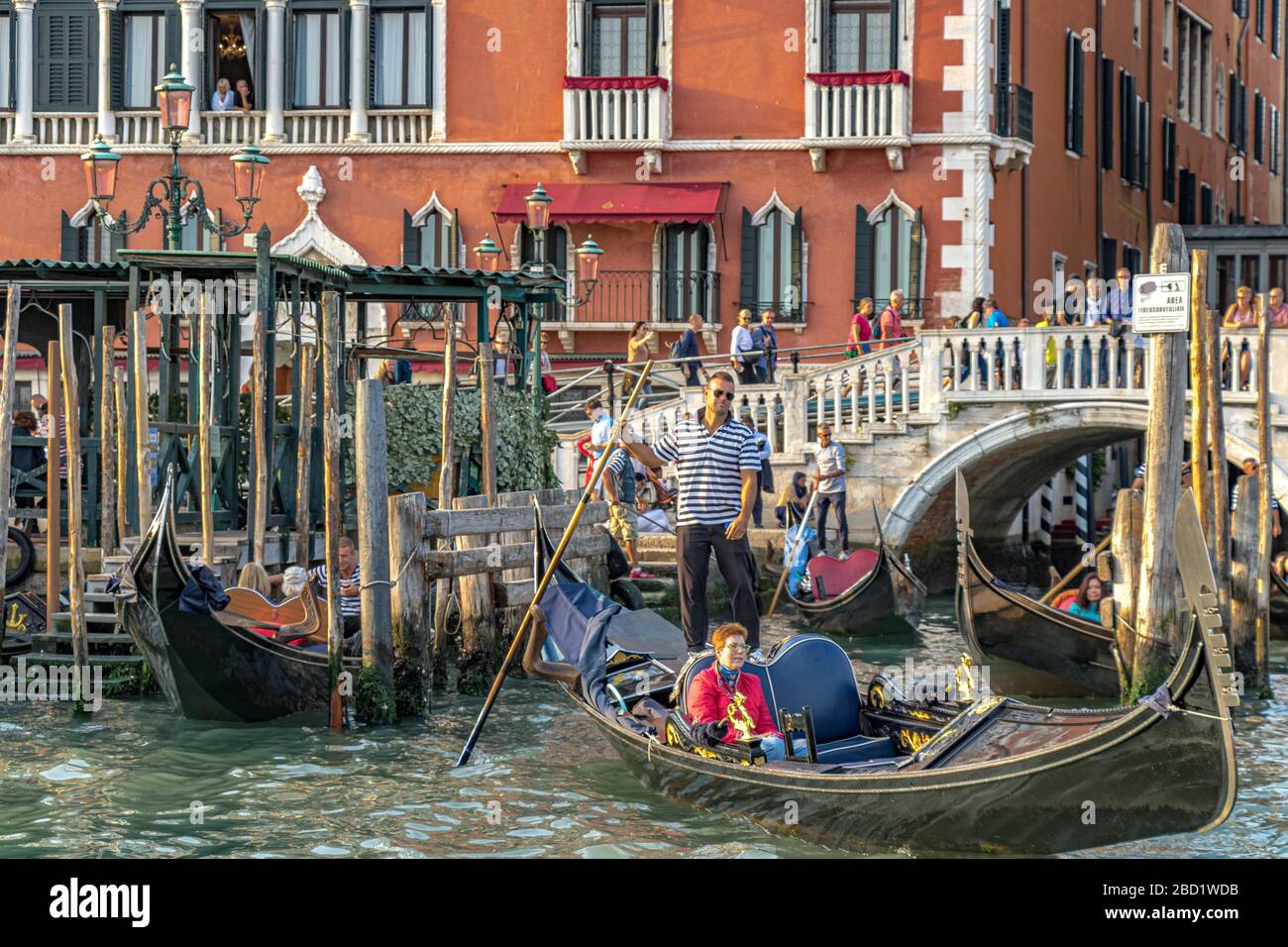 Deux personnes regardent depuis un balcon à l'hôtel Danieli comme Gondoliers prendre les touristes pour une balade en gondole sur le Grand Canal, Venise Italie Banque D'Images