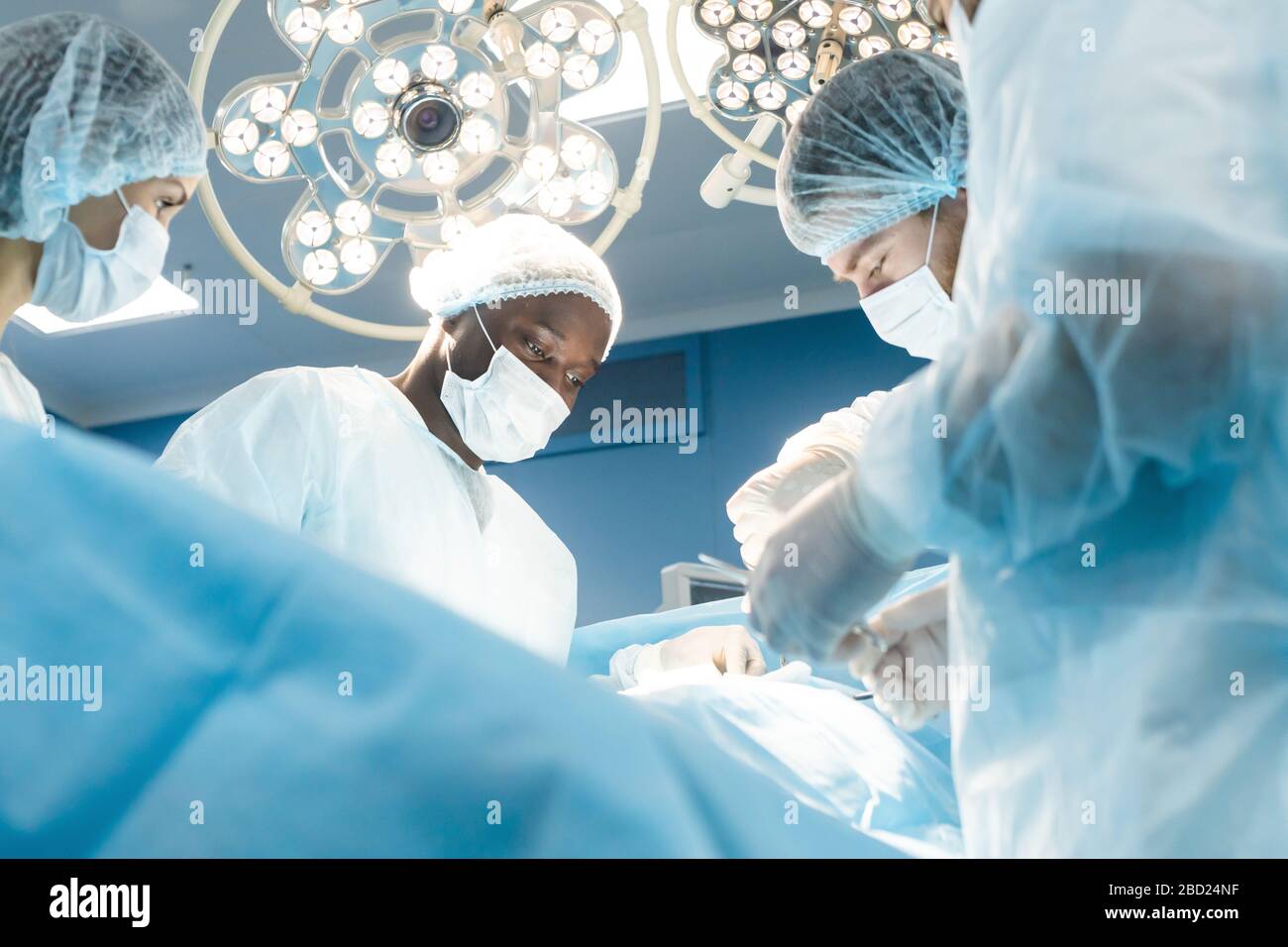 Une équipe internationale de médecins effectue une opération chirurgicale complexe sur un patient sous anesthésie. Salle d'opération moderne et chirurgiens expérimentés Banque D'Images