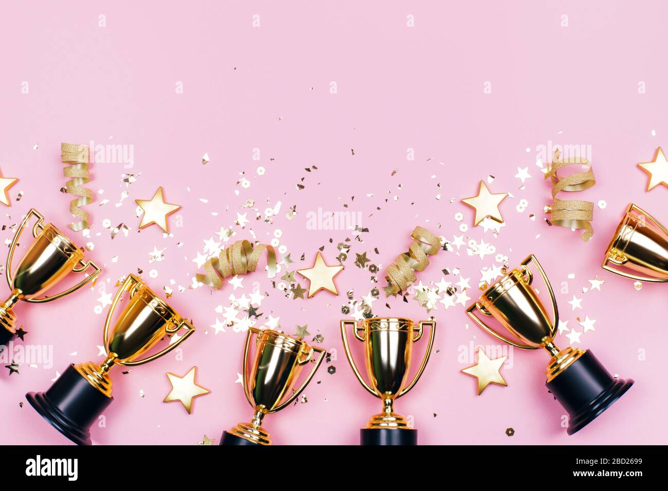 Des coupes de vainqueur avec des confettis et des étoiles festives sur un fond pastel avec un espace de copie sur le dessus. Style plat. Banque D'Images