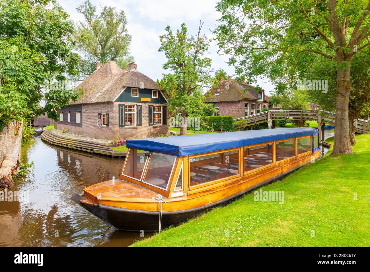 Bateau de croisière sur les canaux vide devant de vieilles maisons dans le village néerlandais de Giethoorn Banque D'Images