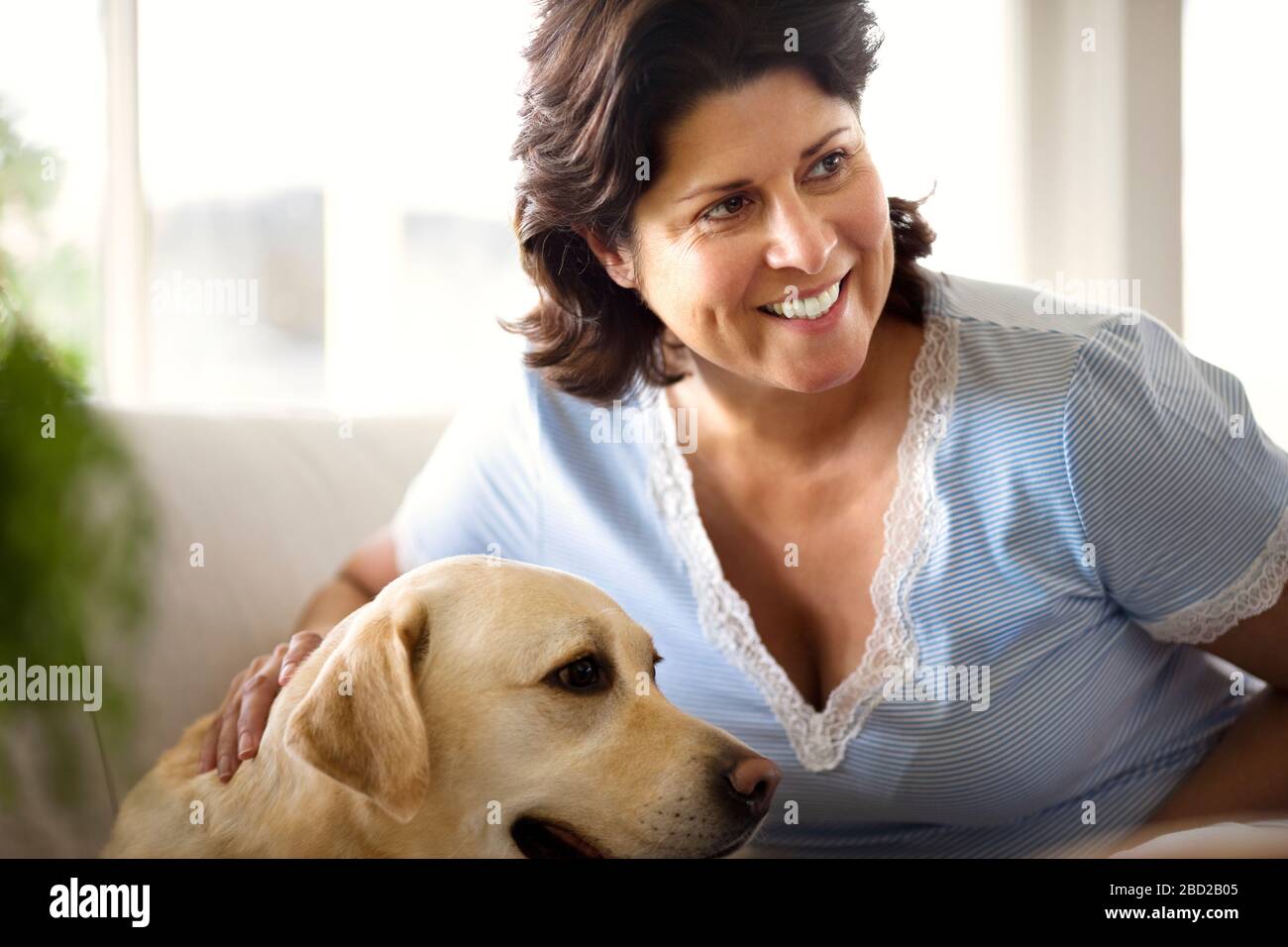 Heureuse femme mûre se reposant avec son labrador doré. Banque D'Images