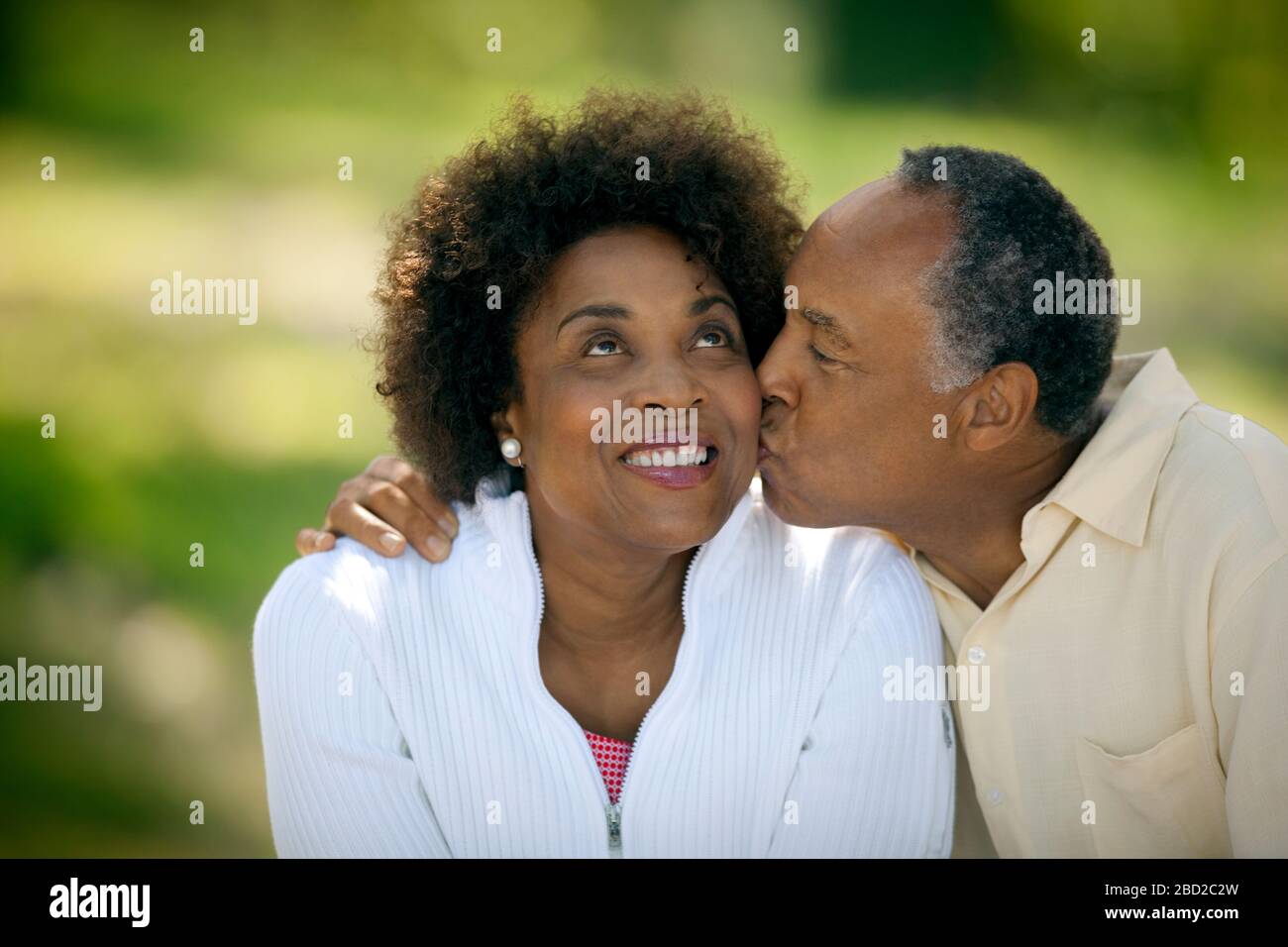 Un homme mûr heureux donne à sa femme souriante un baiser sur la joue. Banque D'Images