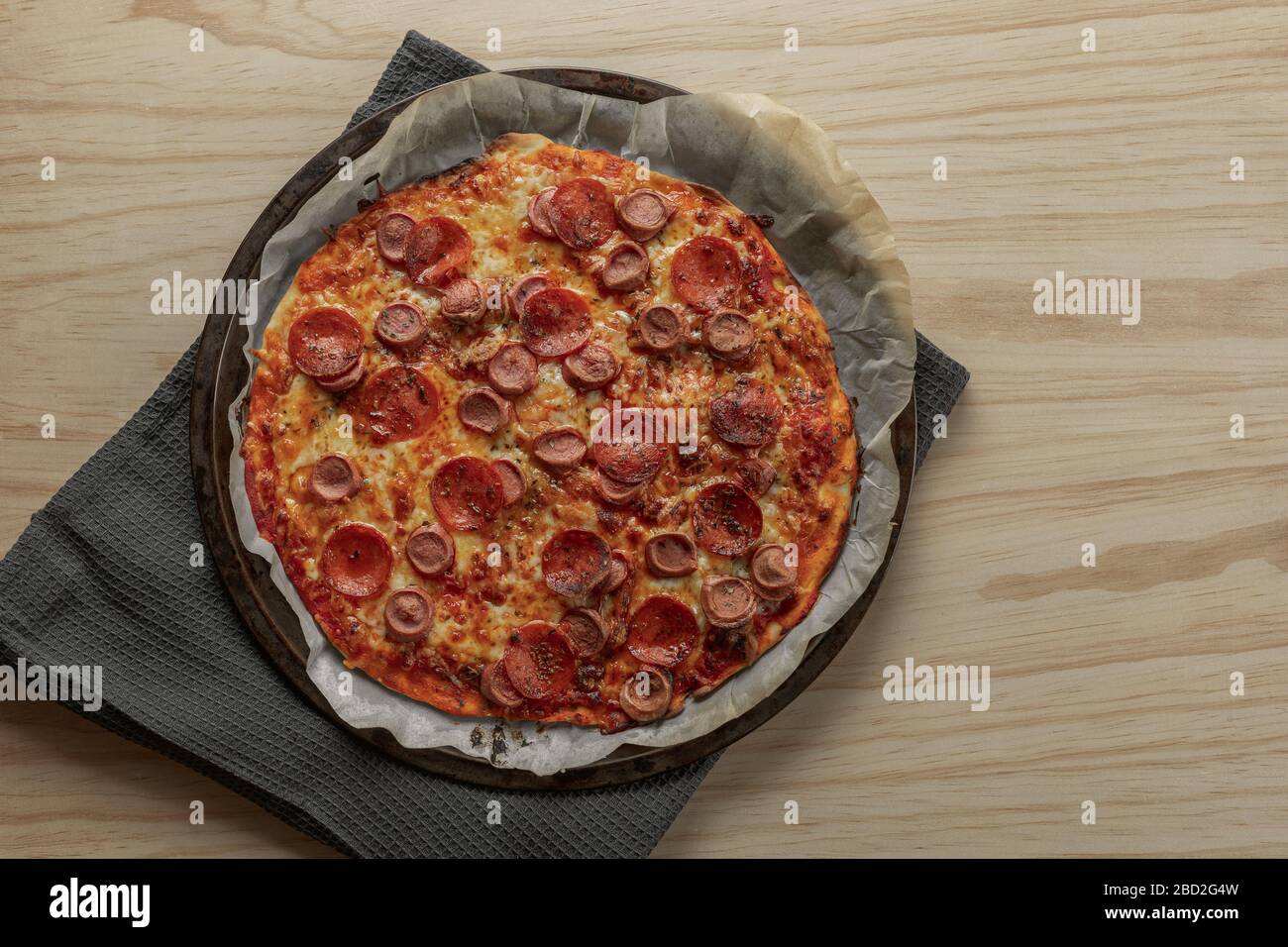 Photographie aérienne d'une pizza maison au poivre et à la saucisse sur plateau métallique avec une serviette noire dans une table en bois Banque D'Images