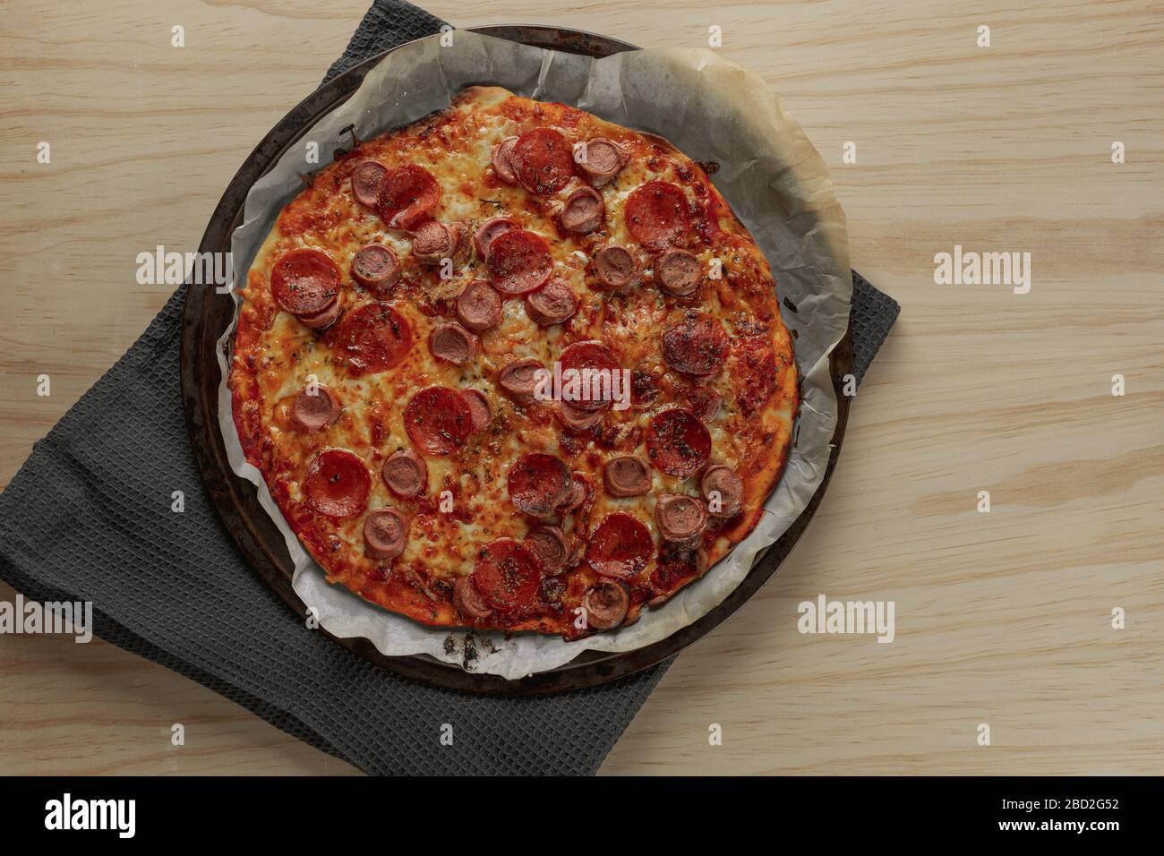 Photographie aérienne d'une pizza maison au poivre et à la saucisse sur plateau métallique avec une serviette noire dans une table en bois Banque D'Images