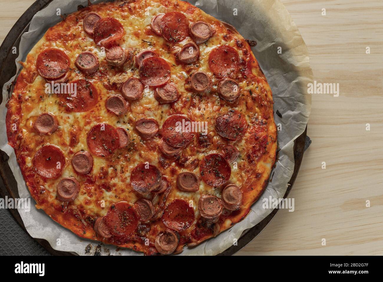 Photographie aérienne d'une pizza maison au poivre et à la saucisse sur plateau métallique avec une serviette noire dans une table en bois Banque D'Images
