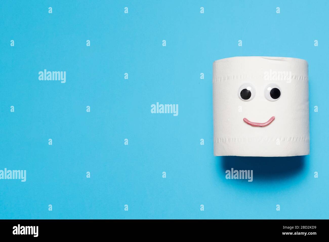 Joyeux et souriant rouleau plein de papier toilette avec des yeux et la bouche sur un fond bleu avec espace de copie et de la place pour le texte Banque D'Images