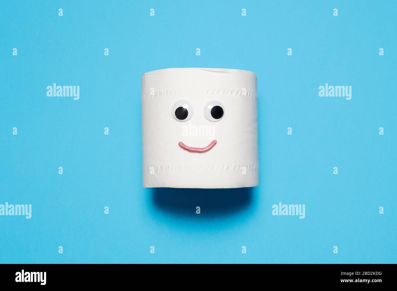 Joyeux et souriant rouleau plein de papier toilette avec des yeux et la bouche sur un fond bleu avec espace de copie et de la place pour le texte Banque D'Images