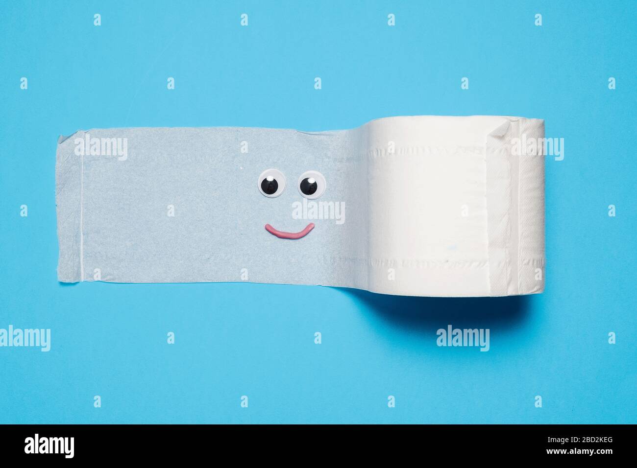 Joyeux et souriant rouleau plein de papier toilette avec des yeux et la bouche sur un fond bleu avec espace de copie et de la place pour le texte Banque D'Images