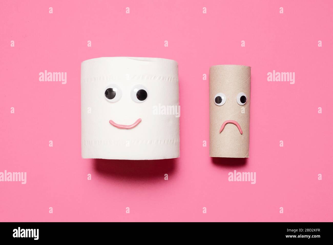 Joyeux et souriant rouleau plein de papier toilette à côté de triste rouleau vide avec des yeux et la bouche sur un fond rose avec espace de copie et de la place pour le texte. Banque D'Images