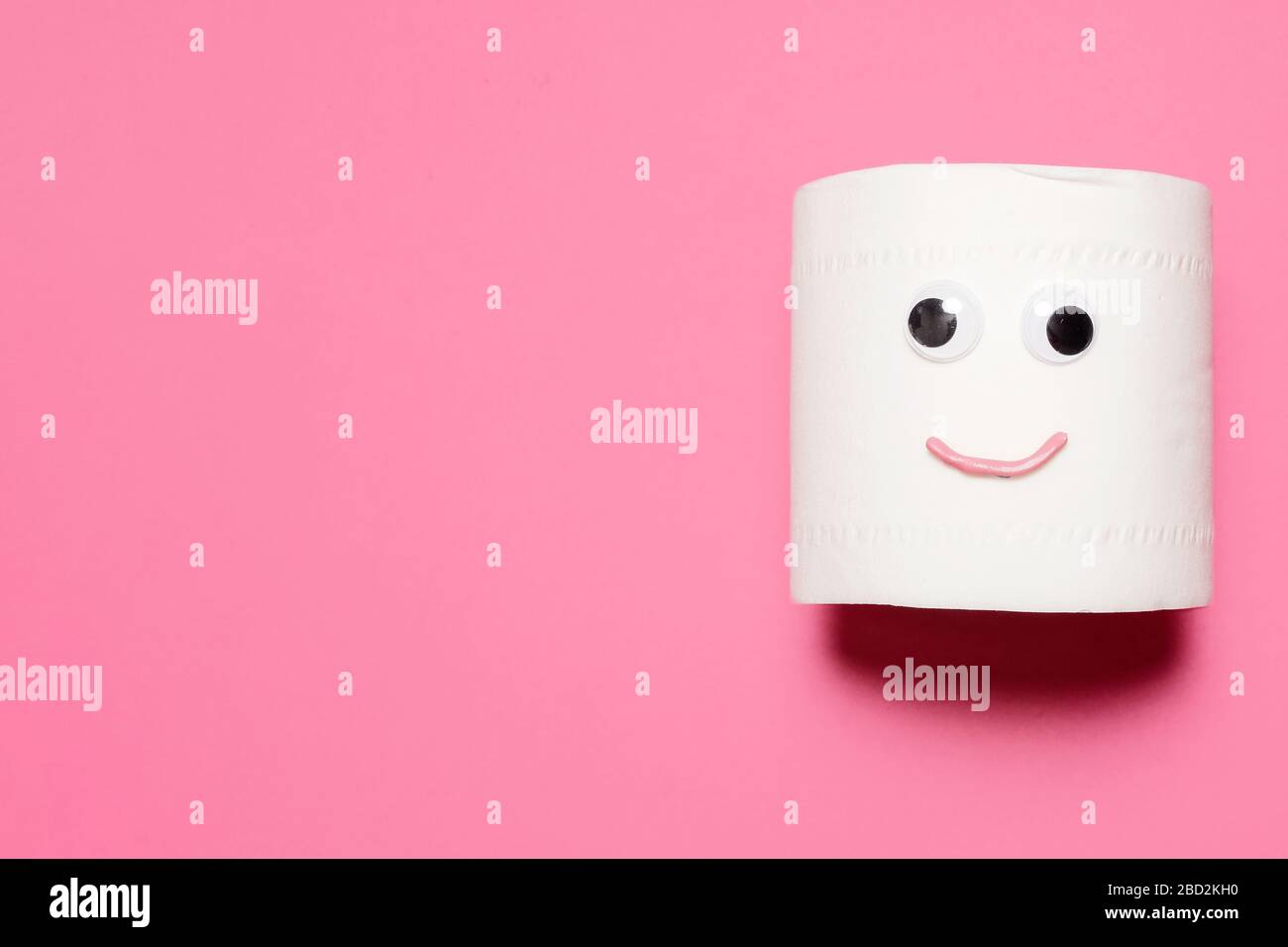 Joyeux sourire plein rouleau de papier toilette avec des yeux et la bouche googly sur un fond rose avec espace de copie et de la place pour le texte Banque D'Images