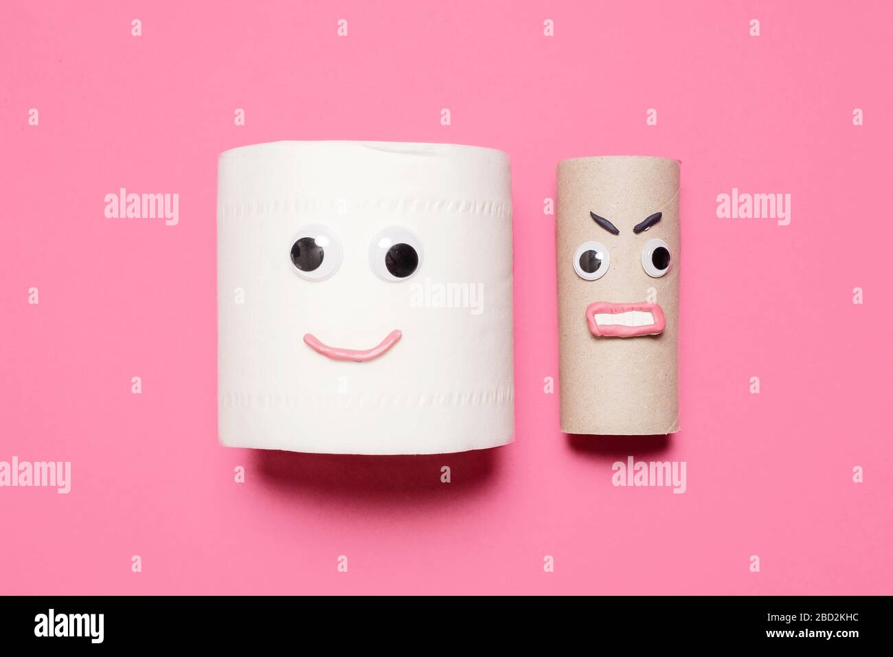 Joyeux sourire plein rouleau de papier toilette à côté de rouleau vide en colère avec des yeux et la bouche sur un fond rose avec espace de copie et de la place pour le texte Banque D'Images