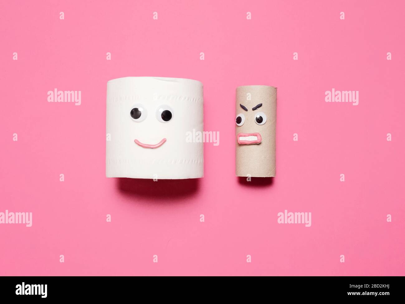 Joyeux sourire plein rouleau de papier toilette à côté de rouleau vide en colère avec des yeux et la bouche sur un fond rose avec espace de copie et de la place pour le texte Banque D'Images