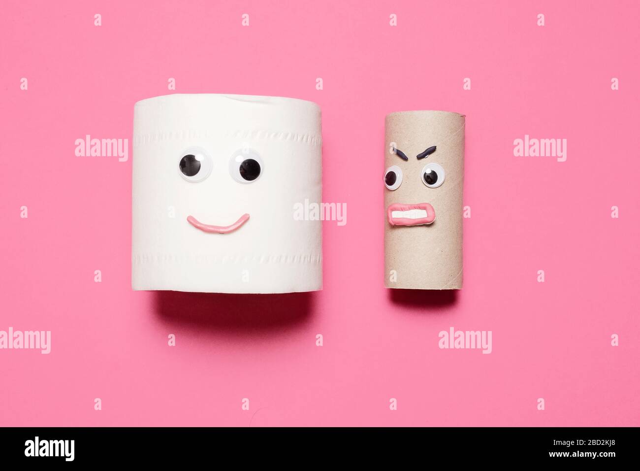 Joyeux sourire plein rouleau de papier toilette à côté de rouleau vide en colère avec des yeux et la bouche sur un fond rose avec espace de copie et de la place pour le texte Banque D'Images