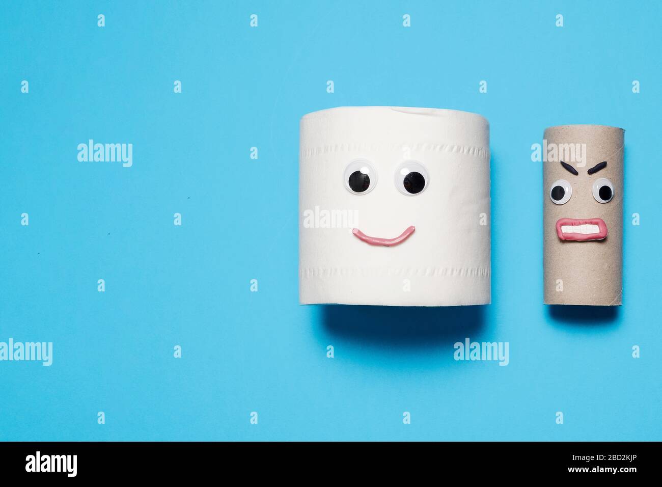 Joyeux sourire plein rouleau de papier toilette à côté de rouleau vide en colère avec des yeux et la bouche sur un fond bleu avec espace de copie et de la place pour le texte Banque D'Images