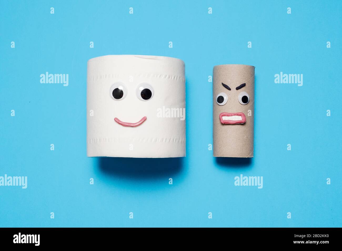 Joyeux sourire plein rouleau de papier toilette à côté de rouleau vide en colère avec des yeux et la bouche sur un fond bleu avec espace de copie et de la place pour le texte Banque D'Images