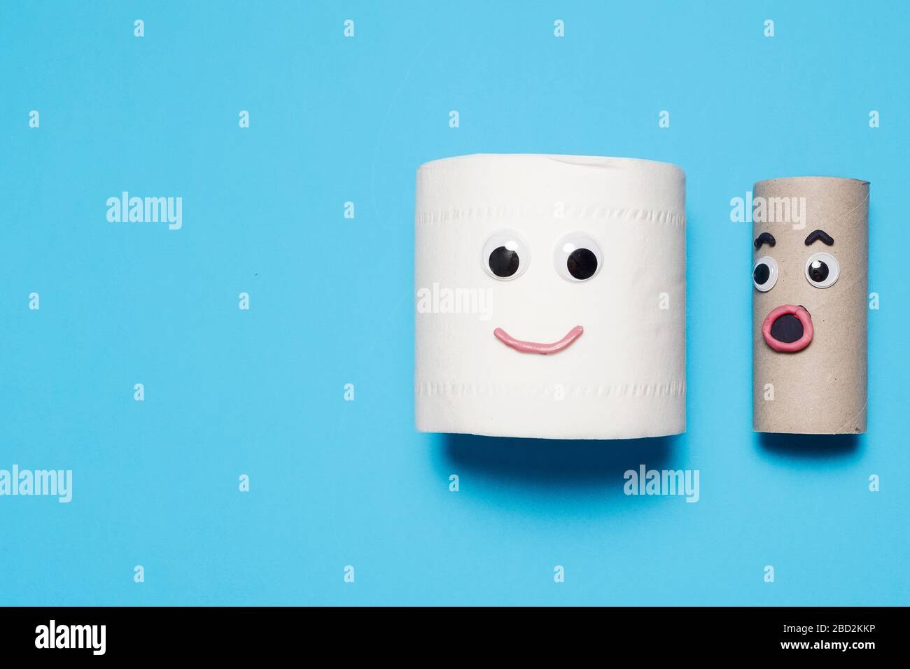 Joyeux sourire plein rouleau de papier toilette à côté de surprise rouleau vide avec des yeux et la bouche googly sur un fond bleu avec espace de copie et de la place pour le texte Banque D'Images