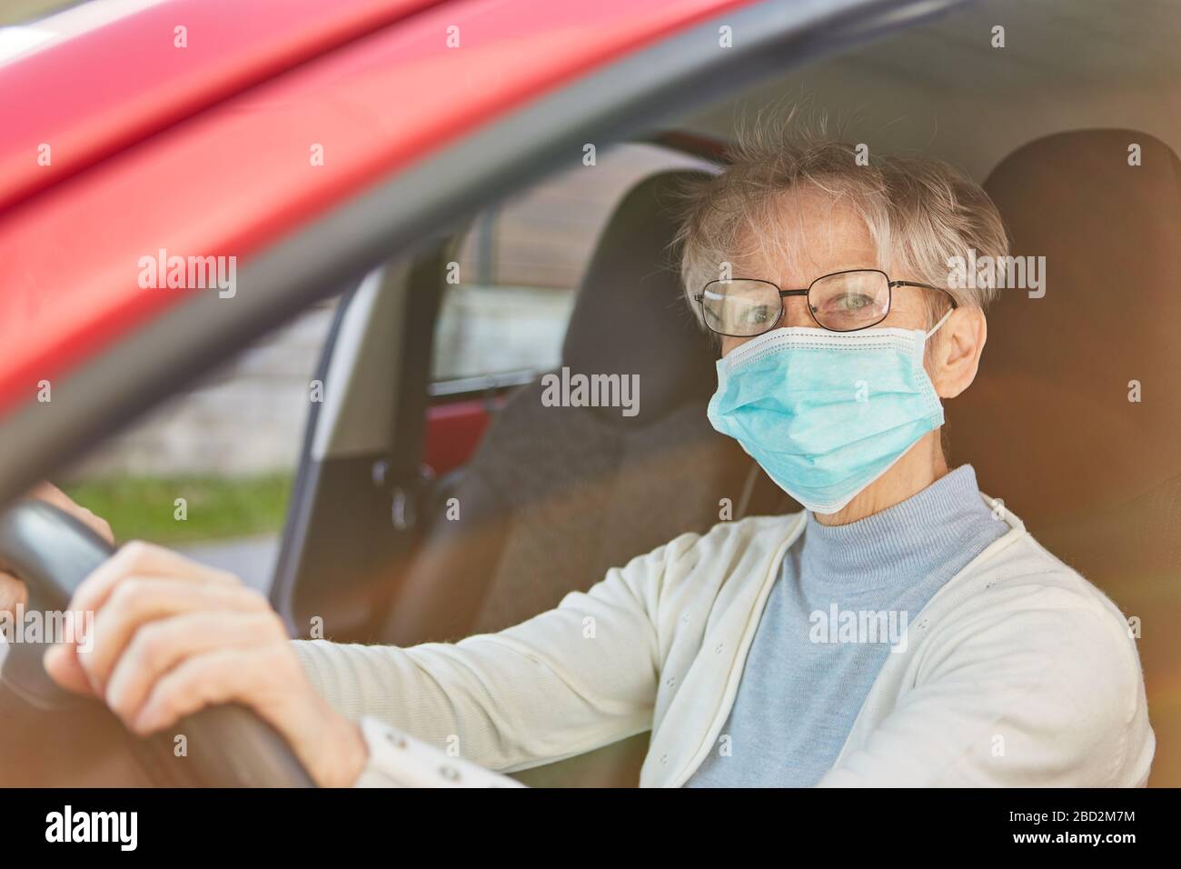 Les personnes âgées en tant que groupe de risque Covid-19 avec protection de la bouche lors de la conduite d'une voiture en cas de pandémie de coronavirus Banque D'Images