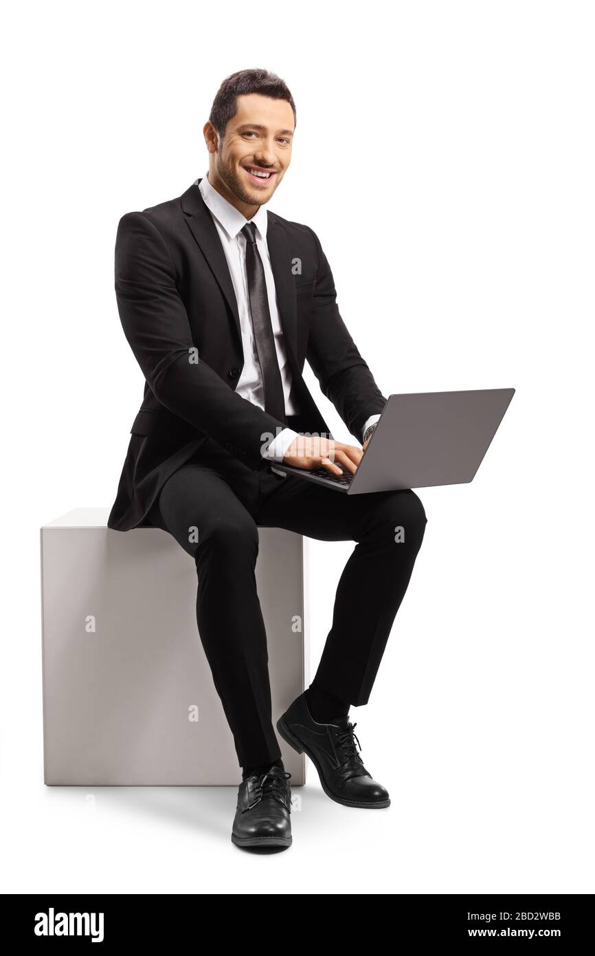 Homme d'affaires assis et à l'aide d'un ordinateur portable, regardant et souriant à l'appareil photo isolé sur fond blanc Banque D'Images