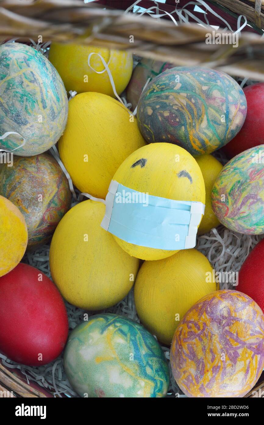 Panier avec œufs colorés et un œuf jaune avec masque de protection Banque D'Images