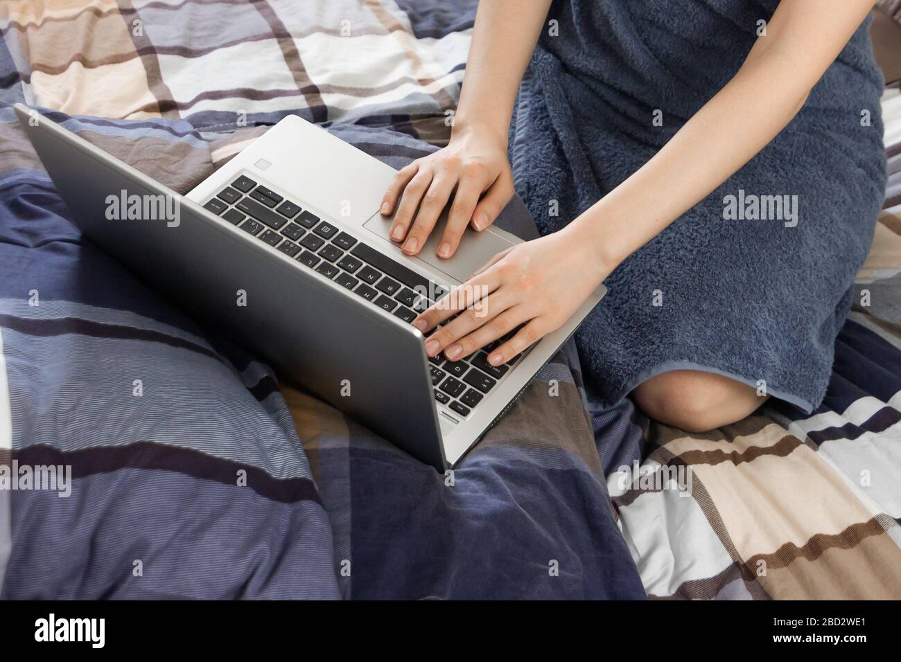 Gros plan sur le pavé tactile d'un ordinateur portable. Une jeune femme recherche sur Internet après le bain. Utilisation d'un ordinateur portable dans une chambre à coucher. Banque D'Images