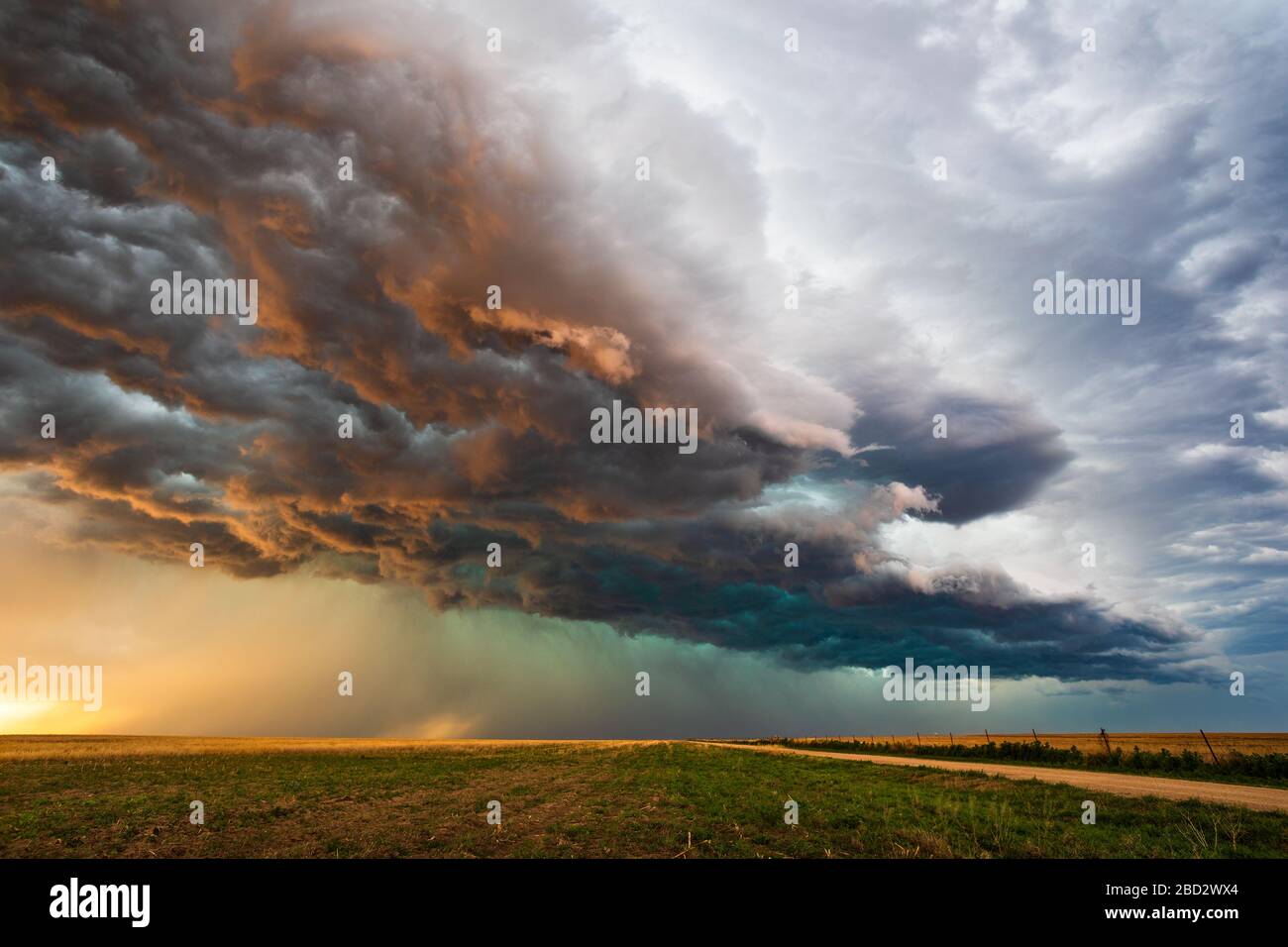 La lumière du soleil illumine des nuages de tempête sombres et spectaculaires sur un champ au coucher du soleil alors qu'une tempête de grêle approche d'EADS, Colorado Banque D'Images