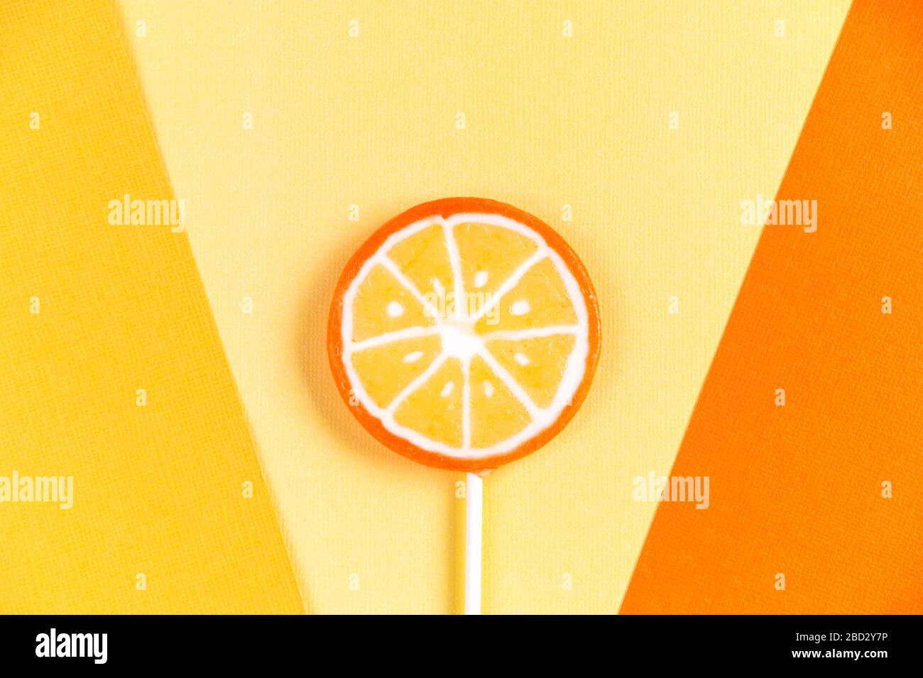 Lollipop orange sur une clé en bois sur fond de papier jaune. Mise au point sélective. Banque D'Images