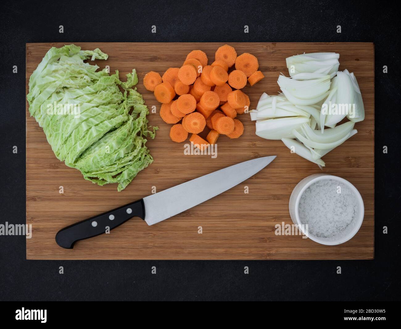 chou, oignon, carottes et couteau de cuisine sur planche en bois de coupe. vue de dessus Banque D'Images