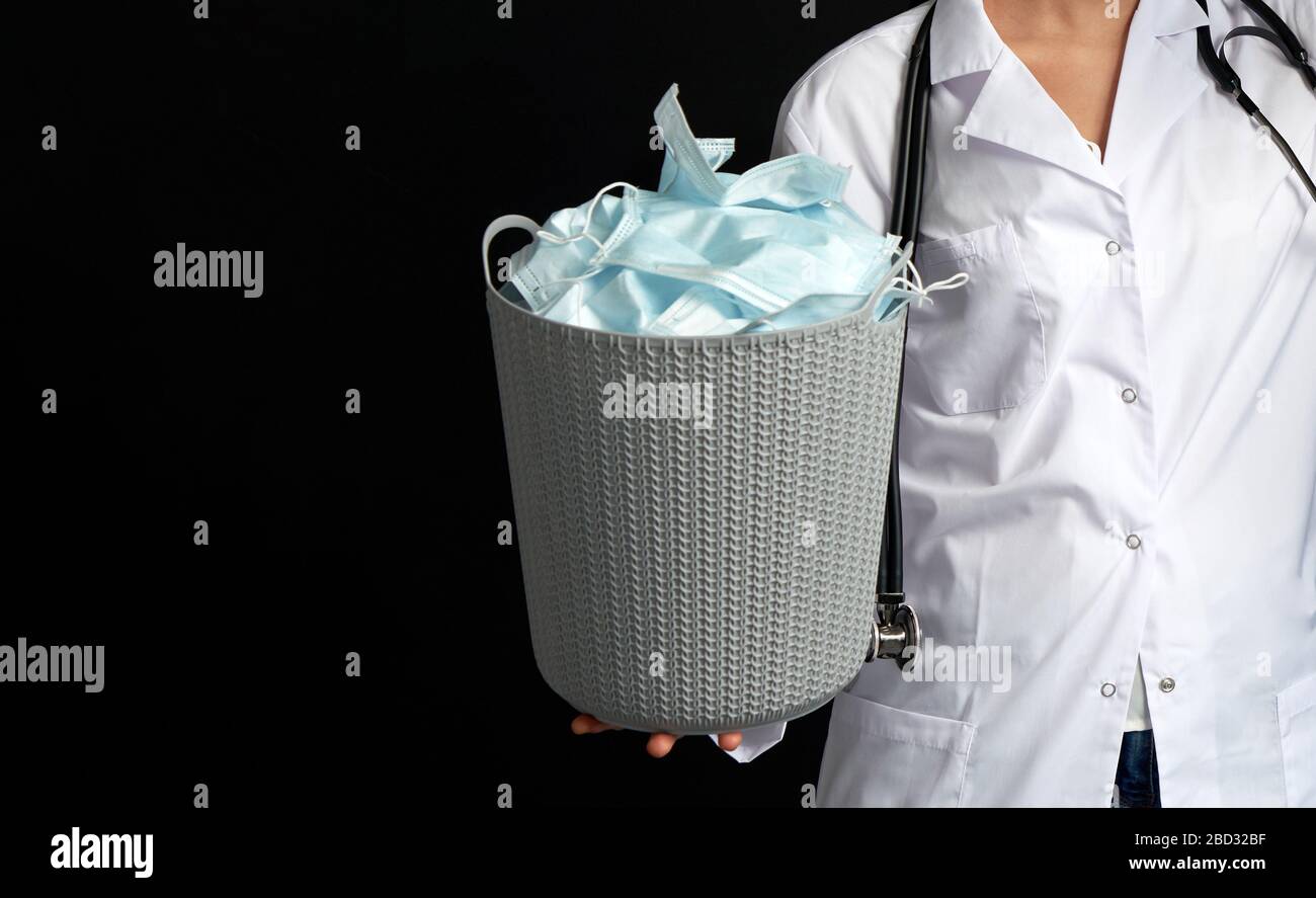 Le médecin tient un seau rempli de masques faciaux usagés, les jetant comme symbole de fin d'épidémie Banque D'Images